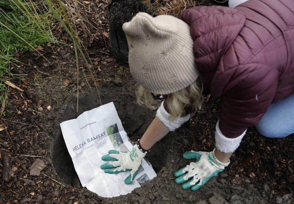 Student Delany Tarr from the Marjory Stoneman Douglas High School in Parkland, Florida, places a student newspaper article in the ground before she plants a tree in honor of the student at Halswell Quarry Park Conservation Area on the outskirts of Christchurch, New Zealand, Tuesday, July 24, 2018. The 28 students who survived the Feb. 14, 2018, mass-shooting at the Florida school are visiting New Zealand to learn more about sustaining youth movements. After planting the native totara trees on Tuesday, they recounted memories of their former classmates and teachers in a ceremony that brought many to tears. (AP Photo/Mark Baker)