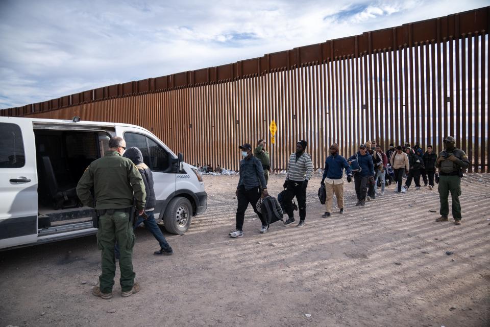 Migrants and asylum seekers are guided into vans to be transported for processing by U.S. Border Patrol agents in Organ Pipe Cactus National Monument along the U.S.-Mexico border about a mile west of Lukeville, Ariz., on Dec. 4, 2023.