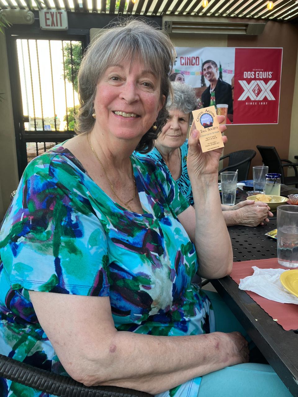 Billie Jean Morison holds a Central Arizona Tall Society business card at Manuel's Mexican Restaurant in Phoenix on April 25, 2023.