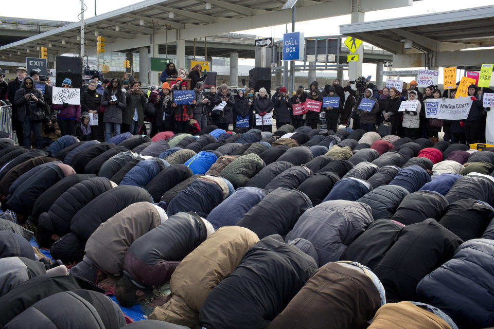 Supporters stand in the background as Muslims participate in a prayer in the parking lot of Terminal 4 at JFK International Airport on February 3, 2017.