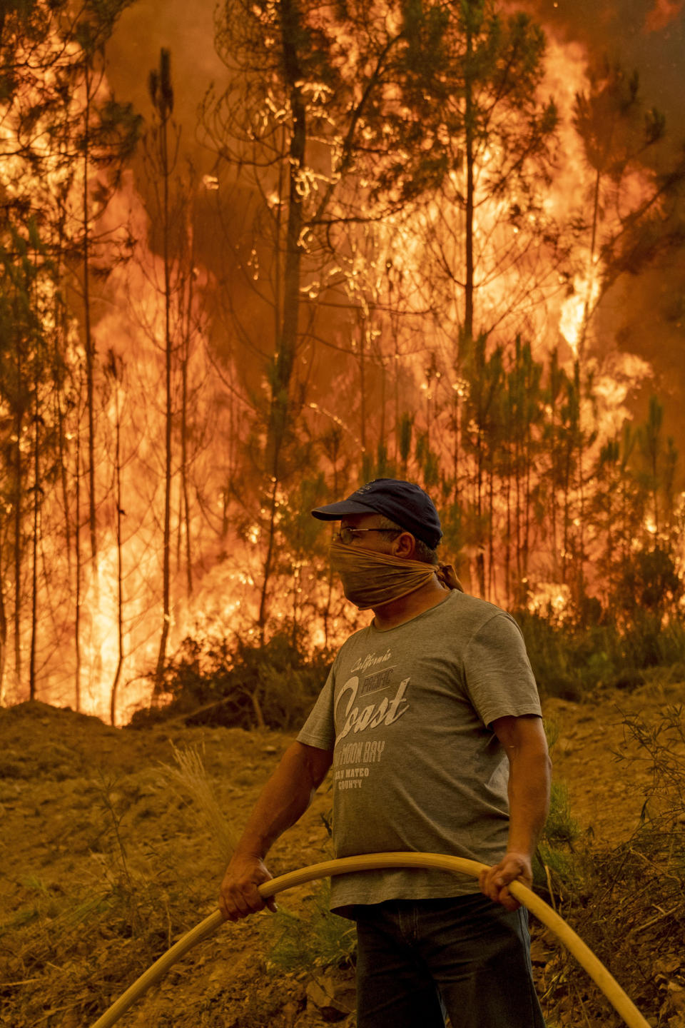 A villager tries to extinguish a wildfire at the village of Chaveira, near Macao, in central Portugal on Monday, July 22, 2019. More than 1,000 firefighters are battling a major wildfire amid scorching temperatures in Portugal, where forest blazes wreak destruction every summer. About 90% of the fire area in the Castelo Branco district, 200 kilometers (about 125 miles) northeast of the capital Lisbon, has been brought under control during cooler overnight temperatures, according to a local Civil Protection Agency commander. (AP Photo/Sergio Azenha)