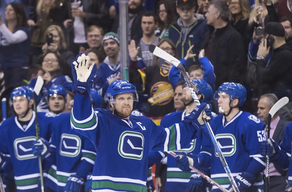 Vancouver Canucks' Henrik Sedin, of Sweden, waves as he receives a standing ovation from his teammates on the bench and the crowd after scoring a goal against the Florida Panthers to record his 1,000th career point, during the second period of an NHL hockey game Friday, Jan. 20, 2017, in Vancouver, British Columbia. (Darryl Dyck/The Canadian Press via AP)