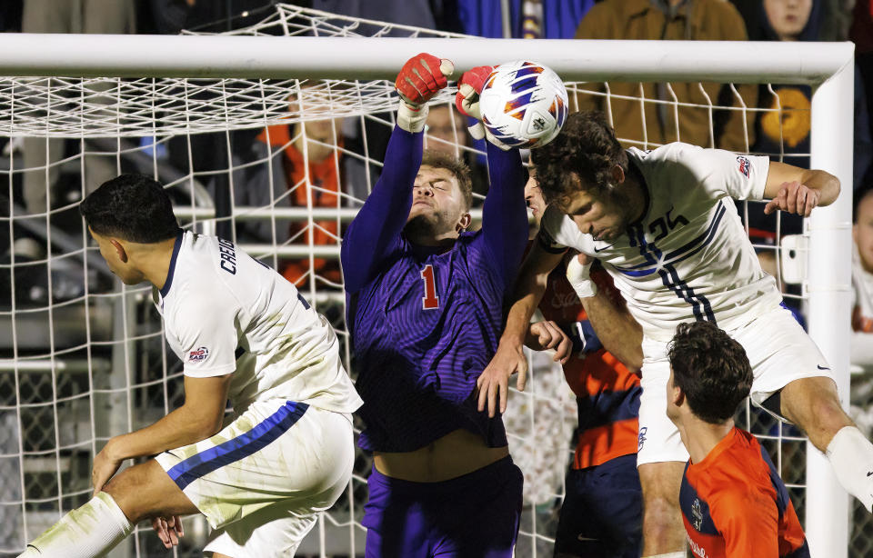 Syracuse's Russell Shealy (1) punches the ball away from the goal between Creighton's Jake Ashford (25) and Luke Mitchell, left, during the second half of an NCAA men's soccer tournament semifinal in Cary, N.C., Friday, Dec. 9, 2022. (AP Photo/Ben McKeown)