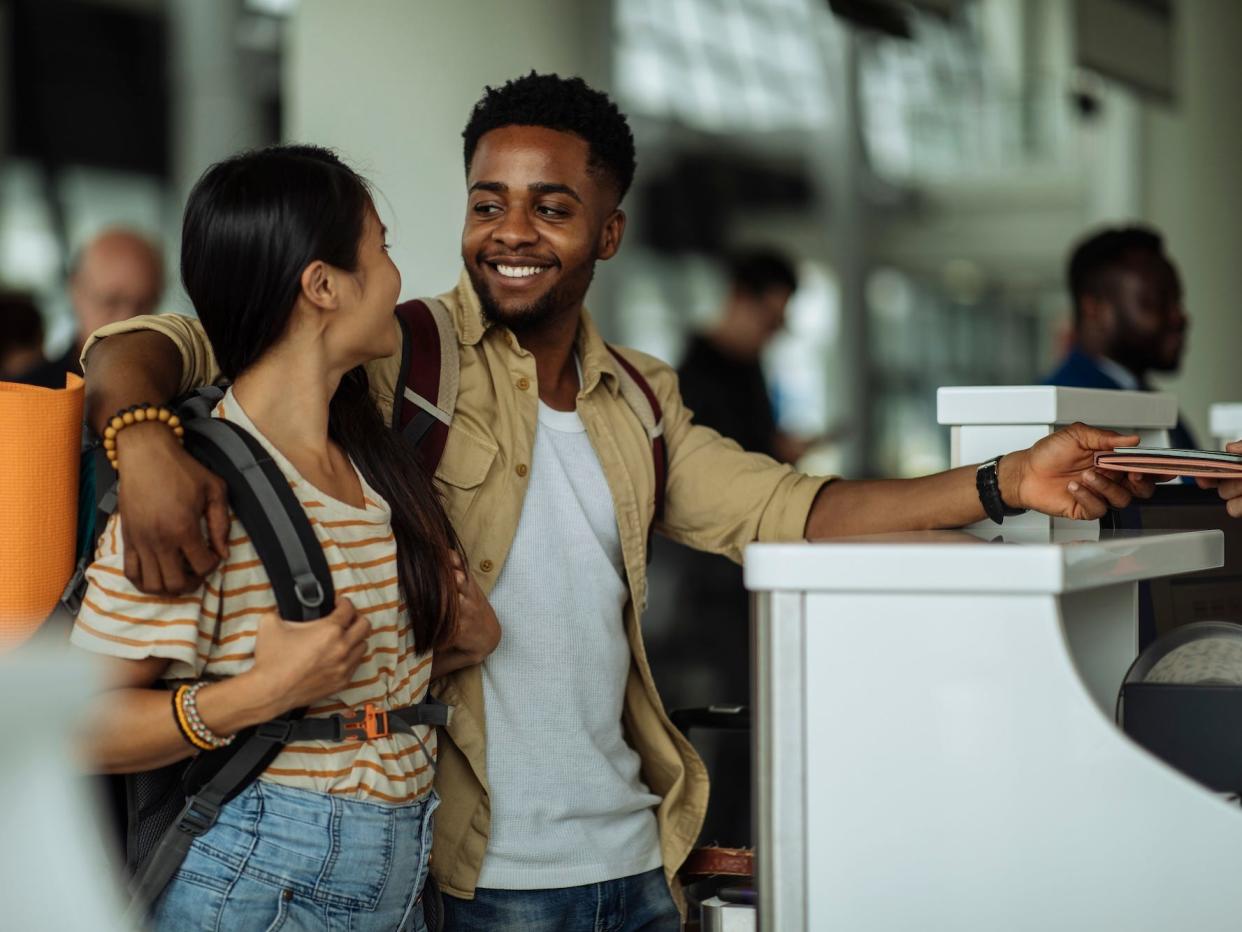 A couple looks at each other as they check in at an airport.