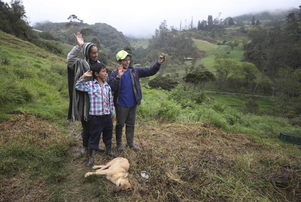 Nubia Rocio Gaona, 37, and her sons, David, 14, right, and Jeimmer, 9, record themselves for their online followers, in Chipaque, Colombia, Saturday, May 9, 2020. The small-time farming mother and two sons are reinventing themselves as YouTubers due to a quarantine ordered by the government to contain the spread of COVID-19, teaching others how to grow vegetables at home and providing self-starter kits that they deliver through a local courier. (AP Photo/Fernando Vergara)