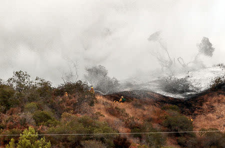 Water falls on firefighters as they evaluate a hillside during the La Tuna Canyon fire over Burbank, California, September 3, 2017. REUTERS/ Kyle Grillot
