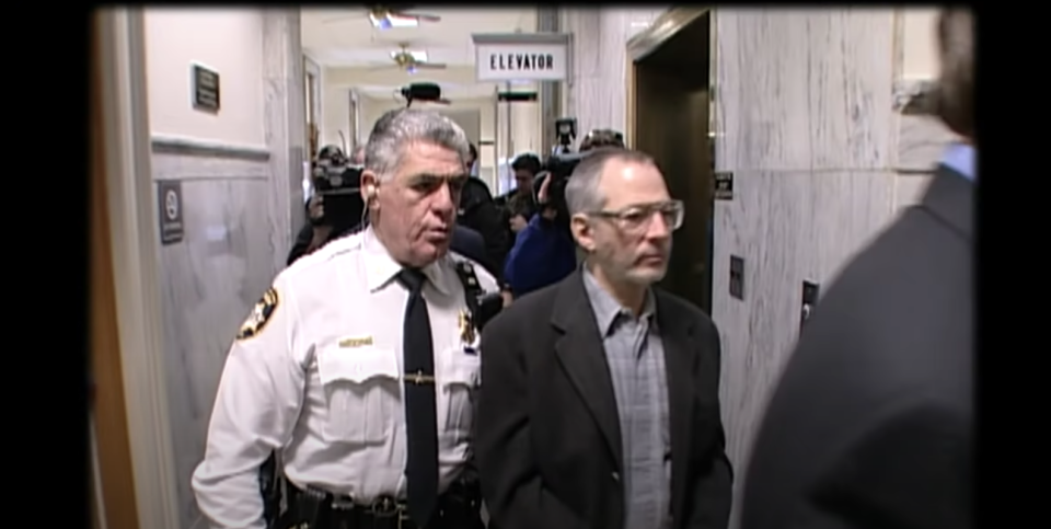 Police escort a man into a courtroom