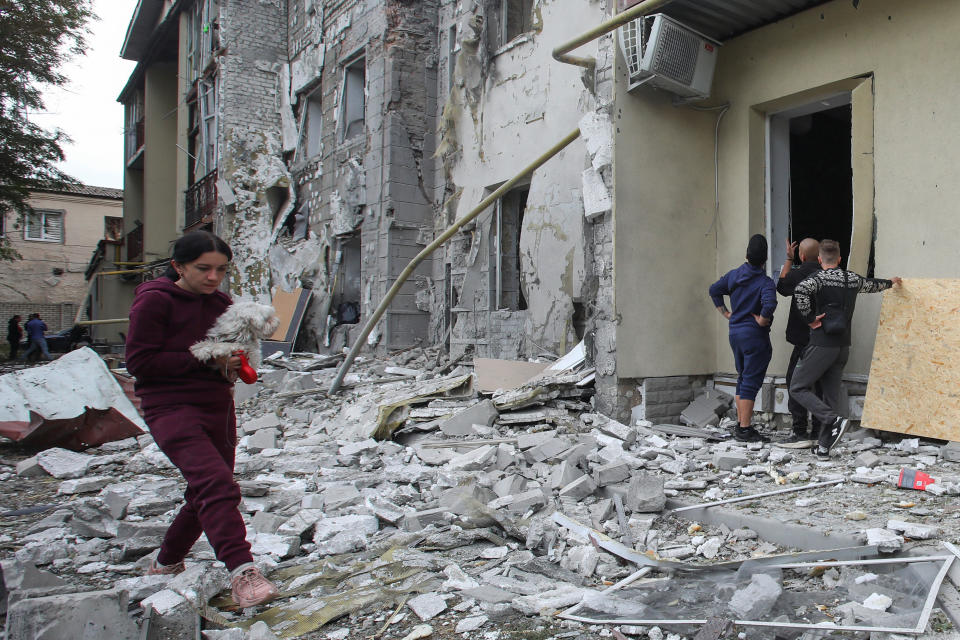 A woman carries a dog in a front of a residential building damaged by a Russian missile strike, amid Russia's attack on Ukraine, in Kharkiv, Ukraine September 12, 2022.  REUTERS/Vyacheslav Madiyevskyy