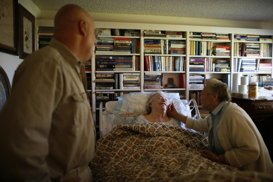 Constantine Moundalexis, 55, (L) watches as a Meals on Wheels volunteer greets his house-bound mother, Catherine Morgan, 82, in Sun City, Arizona, January 5, 2013. Moundalexis moved next door to his mother to take care of her during the final stage of her life. Sun City was built in 1959 by entrepreneur Del Webb as America's first active retirement community for the over-55's. Del Webb predicted that retirees would flock to a community where they were given more than just a house with a rocking chair in which to sit and wait to die. Today's residents keep their minds and bodies active by socializing at over 120 clubs with activities such as square dancing, ceramics, roller skating, computers, cheerleading, racquetball and yoga. There are 38,500 residents in the community with an average age 72.4 years.    Picture taken January 5, 2013.  REUTERS/Lucy Nicholson (UNITED STATES - Tags: SOCIETY)    ATTENTION EDITORS - PICTURE 22 OF 30 FOR PACKAGE 'THE SPORTY SENIORS OF SUN CITY'  SEARCH 'SUN CITY' FOR ALL IMAGES