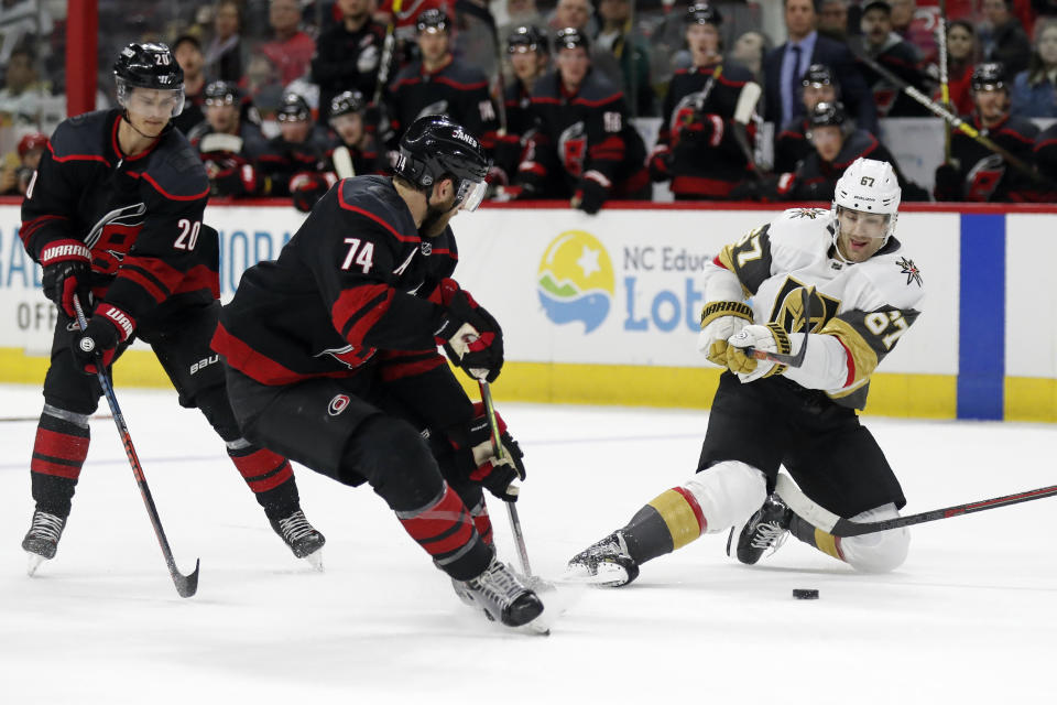 Carolina Hurricanes defenseman Jaccob Slavin (74) chases the puck as Vegas Golden Knights left wing Max Pacioretty (67) goes to the ice during the third period of an NHL hockey game in Raleigh, N.C., Friday, Jan. 31, 2020. center Sebastian Aho (20), of Finland, is at left. (AP Photo/Gerry Broome)