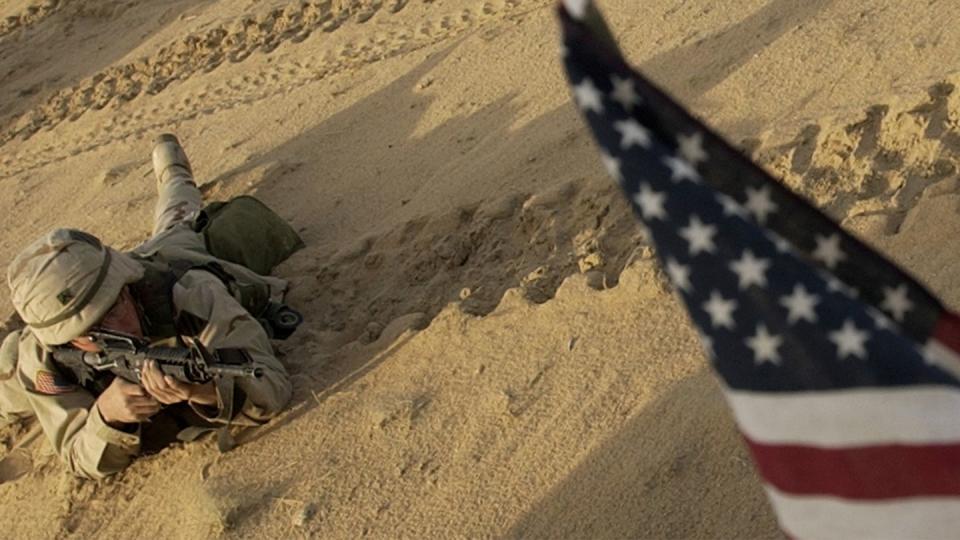 This Jan. 25, 2003 file photo shows an US soldier lying with his rifle in front of an American flag that hangs from a Humvee during live fire exercises in the Kuwaiti desert south of Iraq. (Laura Rauch/AP)