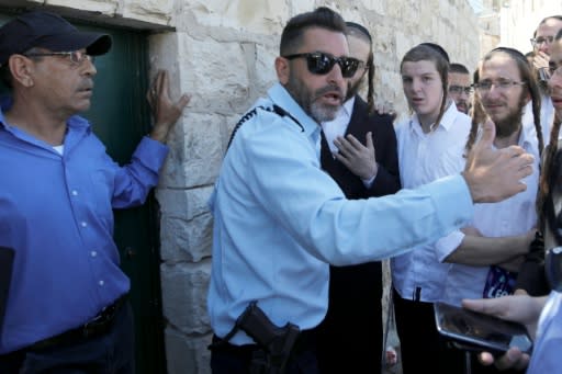 An Israeli policeman prevents Ultra-Orthodox Jewish men from entering the Tombs of the Kings site in Jerusalem owned and administered by the French consulate because they did not pre-register