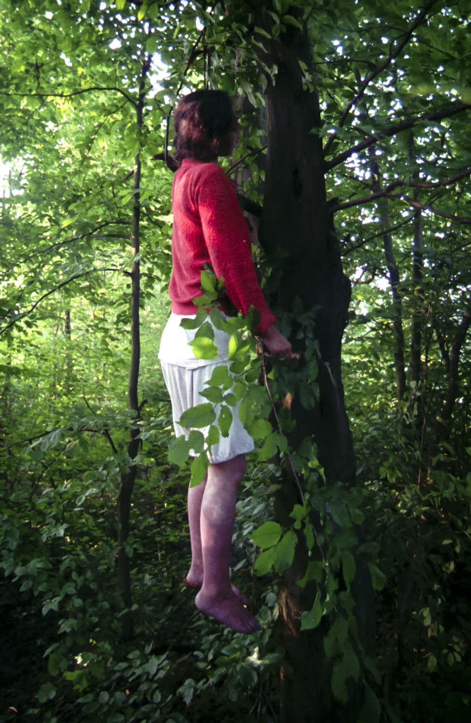 FILE - In this Friday, July 14, 1995, file picture, refugee Ferida Osmanovic, a young woman from Srebrenica, who killed herself using a torn blanket, hangs from a tree in a forest near the U.N. base at Tuzla airport. Survivors of the genocide in the eastern Bosnian town of Srebrenica, mainly women, will on Saturday July 11, 2020, commemorate the 25th anniversary of the slaughter of their fathers and brothers, husbands and sons. At least 8,000 mostly Muslim men and boys were chased through woods in and around Srebrenica by Serb troops in what is considered the worst carnage of civilians in Europe since World War II. The slaughter was also the only atrocity of the brutal war that has been confirmed an act of genocide.(AP Photo/Darko Bandic, File)