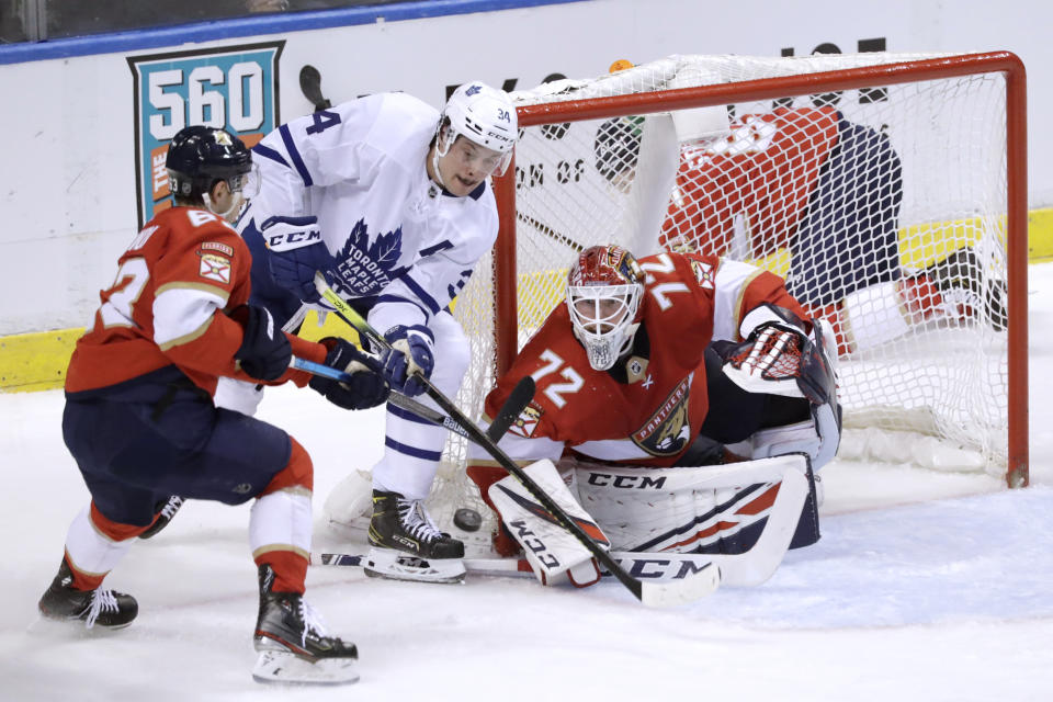 Toronto Maple Leafs center Auston Matthews (34) battles Florida Panthers goaltender Sergei Bobrovsky (72) and right wing Evgenii Dadonov (63) at the net during the second period of an NHL hockey game Thursday, Feb. 27, 2020, in Sunrise, Fla. (AP Photo/Wilfredo Lee)