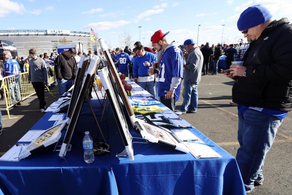 Fans look at items in a silent auction being held to raise money for people suffering from the affects of Superstorm Sandy and cystic fibrosis before an NFL football game between the New York Giants and the Pittsburgh Steelers, Sunday, Nov. 4, 2012, in East Rutherford, N.J. (AP Photo/Julio Cortez)