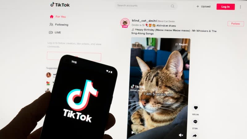 The TikTok logo is seen on a mobile phone in front of a computer screen which displays the TikTok home screen, on March 18, 2023, in Boston. TikTok’s suit against the federal government will be heard in court in September.