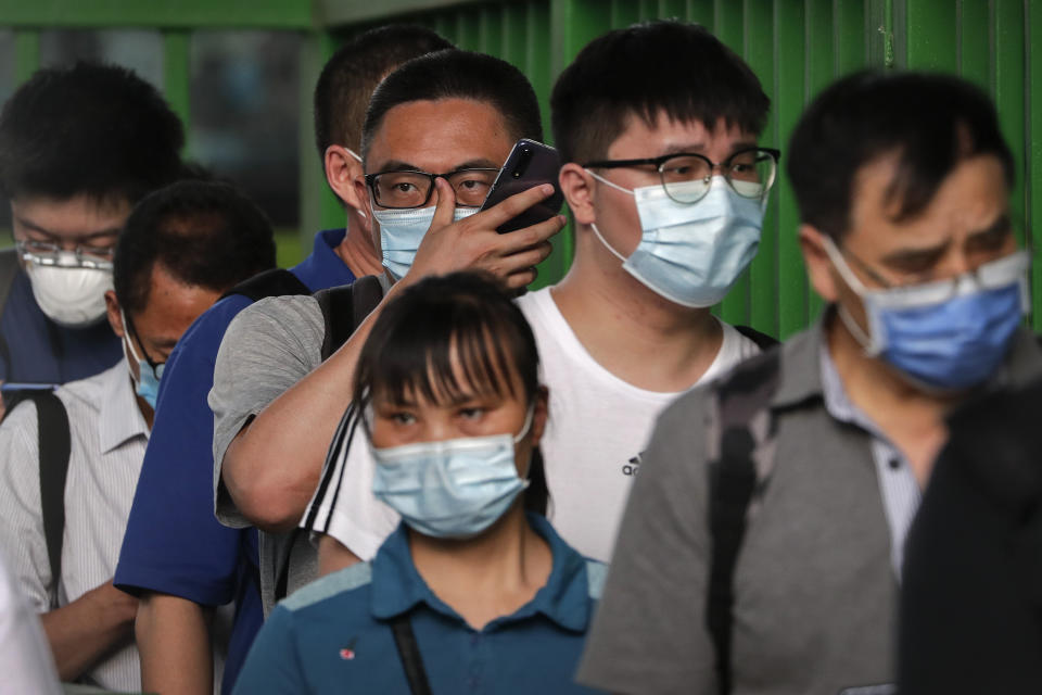 Commuters wearing protective face masks to help curb the spread of the new coronavirus line up to board a bus at a bus terminal in Beijing, Monday, June 22, 2020. A Beijing government spokesperson said the city has contained the momentum of a recent coronavirus outbreak that has infected a few hundreds of people, after the number of daily new cases fell to single digits. (AP Photo/Andy Wong)