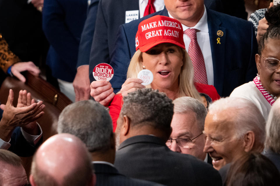 WASHINGTON - MARCH 7: Rep. Marjorie Taylor Greene, R-Ga., flashes a Laken Riley button while wearing her Make America Great Again hat to President Joe Biden as he arrives in the House chamber to deliver the State of the Union Address to the joint session of Congress in the U.S. Capitol on Thursday, March 7, 2024. (Bill Clark/CQ-Roll Call, Inc via Getty Images)