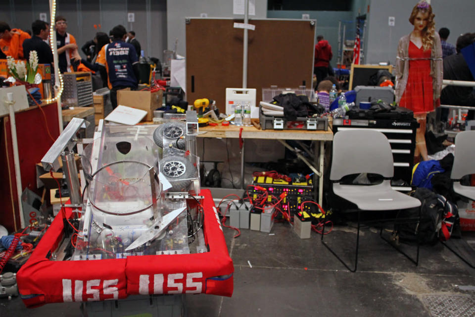 A cardboard cut out of Taylor Swift smiling sweetly at Bronx Science High School’s robot in the pit area.