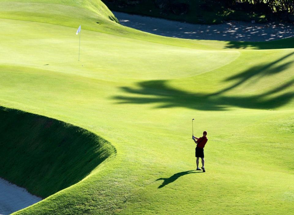 A man plays golf from afar.