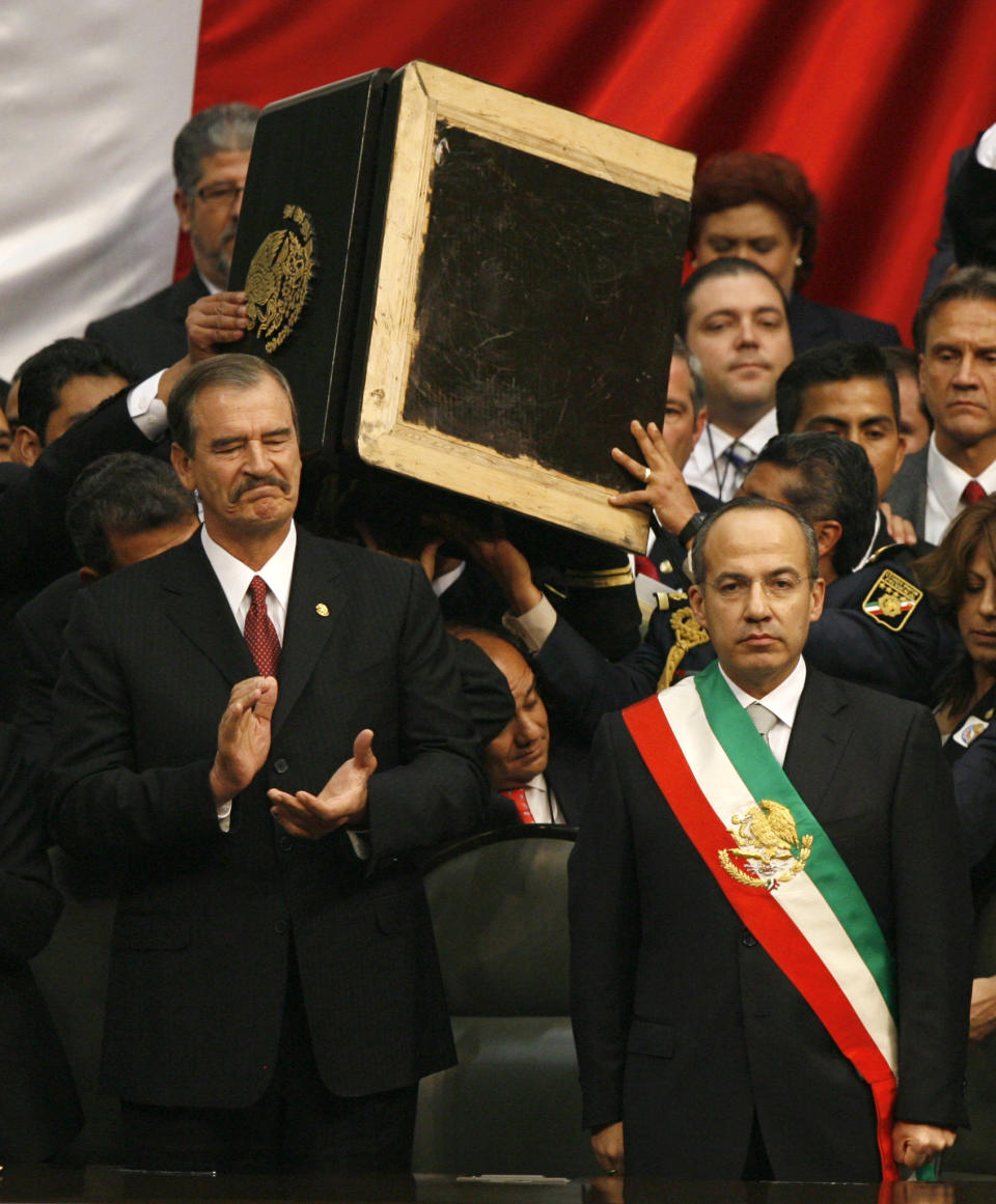 FILE - In this Friday Dec. 1, 2006 file photo, Mexican President Felipe Calderon, right, stands wearing the presidential sash as outgoing president Vicente Fox looks on at the National Congress during his inauguration ceremony amidst a congress partially seized by lawmakers who tried unsuccessfully to block his swearing in ceremony in Mexico City. Calderon asked members of his security to remove the podium so the presidential sash could be seen in its entirety. Mexicans hoped that their country would take a new course under Vicente Fox's center-right National Action Party, or PAN, but despite a more open economy and a bigger middle class, Mexico is torn by drug trafficking violence after a dozen years under the PAN's leadership, first under Fox and then under current President Felipe Calderon, who barely squeaked by in contested 2006 elections. (AP Photo/Dario Lopez-Mills, File)