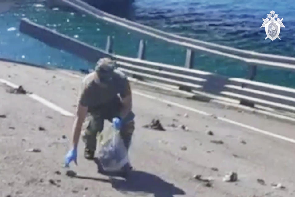 In this handout photo taken from video released by Investigative Committee of Russia on Monday, July 17, 2023, an investigator works at an automobile link of the Crimean Bridge connecting Russian mainland and Crimean peninsula over the Kerch Strait not far from Kerch, Crimea. Traffic on the key bridge connecting Crimea to Russia's mainland was halted on Monday, July 17, after reports of explosions that Crimean officials said were from a Ukrainian attack. (Investigative Committee of Russia via AP)