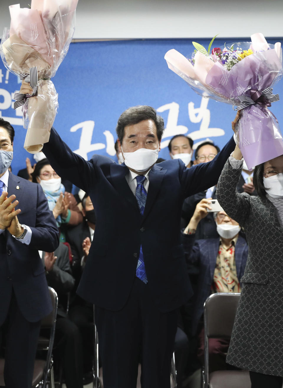 Lee Nak-yon, a former prime minister and candidate of the ruling Democratic Party, holds his hands with flowers after the parliamentary election in Seoul, South Korea, Wednesday, April 15, 2020. South Korean voters wore masks and moved slowly between lines of tape at polling stations on Wednesday to elect lawmakers in the shadows of the spreading coronavirus. (Hong Hae-in/Yonhap via AP)