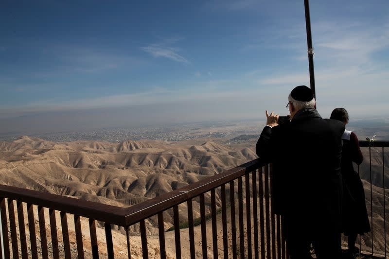 The Palestinian city of Jericho is seen in the background as a Jewish man takes a photograph from a lookout point near the Israeli settlement of Mitzpe Yericho in the Jordan Valley in the Israeli-occupied West Bank