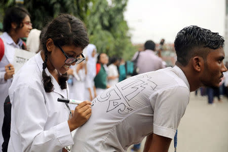 FILE PHOTO: A student writes a slogan on the back of another student as they take part in a protest over recent traffic accidents that killed a boy and a girl, in Dhaka, Bangladesh, August 4, 2018. REUTERS/Mohammad Ponir Hossain