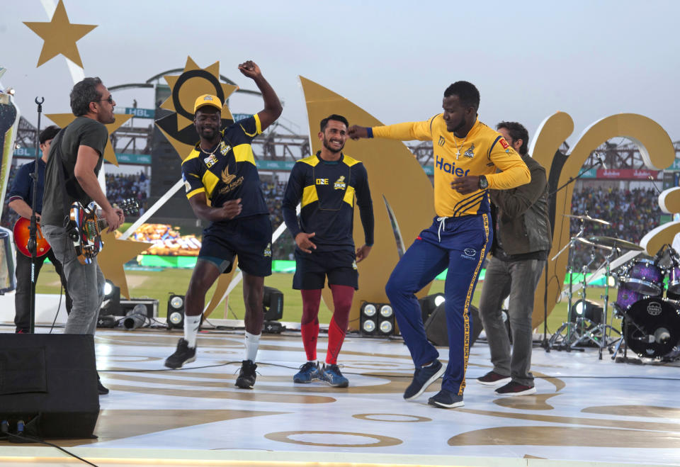FILE - In this March 25, 2018 file photo, West Indies cricketers Darren Sammy, right, Andre Fletcher, second left, and Pakistani cricketer Hassan Ali, center, dance during a music show prior to start of the Pakistan Super League final cricket match at National stadium, in Karachi, Pakistan. The Pakistan Super League is not like any other domestic Twenty20 cricket league around the world. It can't compete financially with the lucrative Indian Premier League in terms of player payments, yet it's a dream for Pakistani cricketer to be part of it. For the Pakistan Cricket Board, the PSL is a pathway to ultimately bring foreign teams back to Pakistan and resume fully-fledged international cricket on home soil. (AP Photo/Fareed Khan, File)