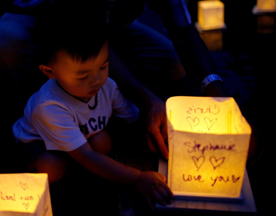 Elliot Qua, 2, puts a lantern in the water during a the Water Lantern Festival at Hafer Park in Edmond, Okla., Saturday, Aug., 20, 2022. 