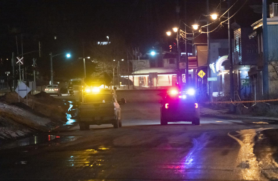 A police car and a Transport Quebec truck guard the perimeter of a fatal accident, in Amqui, Quebec, Monday, March 13, 2023. Two men died after a pickup truck plowed into pedestrians beside a road, although a senior Canadian official rapidly ruled out a terrorism attack or a national security incident. (Jacques Boissinot/The Canadian Press via AP)