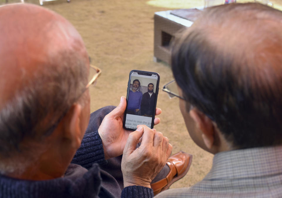 Relatives look the pictures of Pakistani citizen Rashid Naeem, and his son Talha Naeem, who were reportedly killed in the Christchurch mosque shooting, in a cell phone at their native home in Abbottabad, Pakistan, Saturday, March 16, 2019. Pakistan's foreign minister says nine Pakistanis were missing after the mass shootings at two mosques in the New Zealand city of Christchurch. (AP Photo/Aqeel Ahmed)