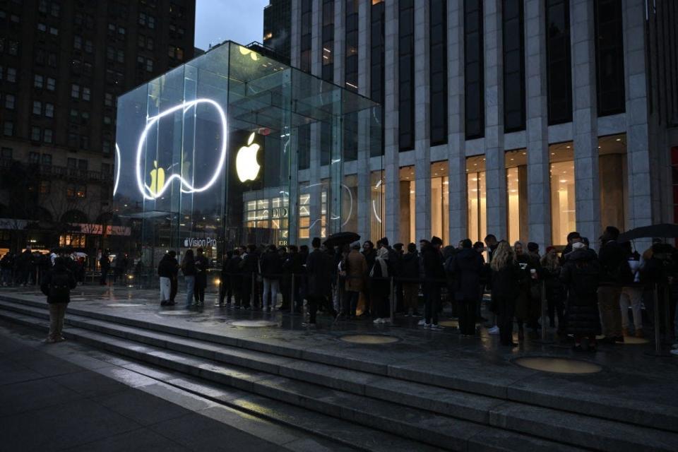 people line up in the early morning hours outside a glowing Apple Store in Manhattan for the Vision Pro launch