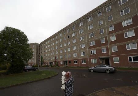 A woman walks outside a building, that also serves as an accommodation facility for refugees and was searched by German police on Tuesday, in the village of Suhl, Germany, October 25, 2016. REUTERS/Kai Pfaffenbach