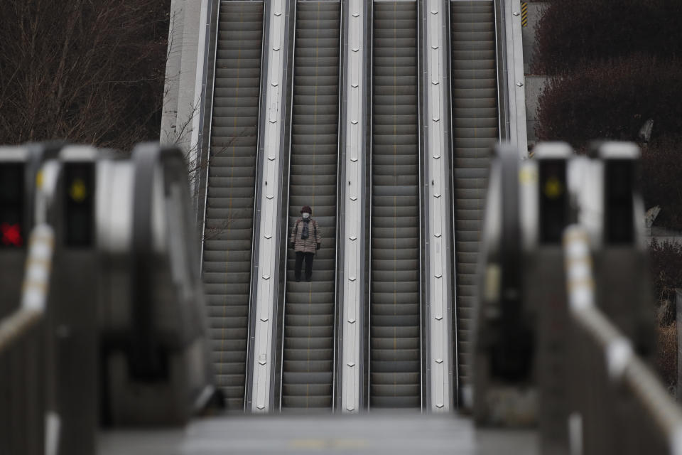 A woman wearing a face mask as a precaution against the coronavirus takes the escalator down in Seoul, South Korea, Thursday, Jan. 21, 2021. (AP Photo/Lee Jin-man)