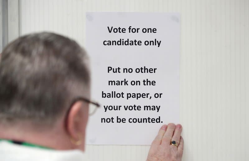 Un trabajador prepara un letrero en una mesa electoral el día de las elecciones generales en Londres