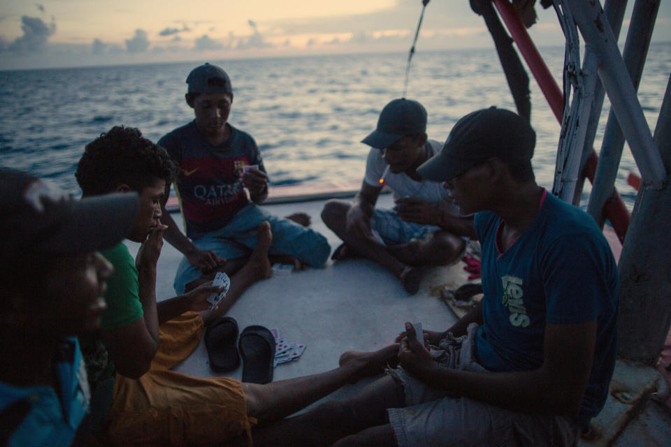 En esta fotografía del 10 de septiembre de 2018, buzos misquitos juegan cartas mientras son llevados a casa luego de un viaje de pesca de dos semanas, cerca de Cayo Savanna, Honduras. (AP Foto/Rodrigo Abd)