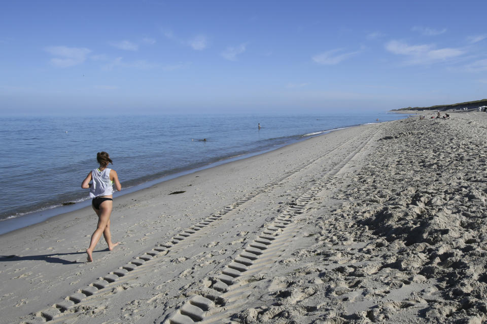 A women jogs at the beach of the vilage of Hoernum on the island Sylt in Germany, Friday, Aug. 3, 2018. (Bodo Marks/dpa via AP)