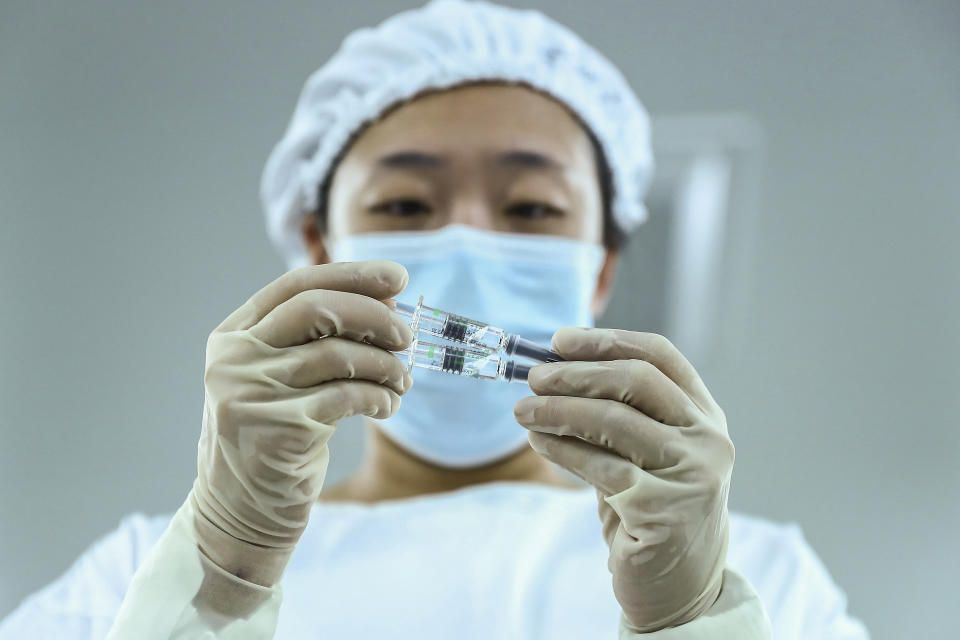 In this photo Dec. 25, 2020 released by Xinhua News Agency, a staff member inspects syringes of COVID-19 inactivated vaccine products at a packaging plant of the Beijing Biological Products Institute Co., Ltd, a unit of state-owned Sinopharm in Beijing. The Chinese drugmaker said Wednesday, Dec. 30, 2020 its coronavirus vaccine was found to be 79.3% effective at preventing infection in preliminary data from the final round of testing, moving Beijing closer to possibly being able to fulfill its pledge to supply other developing countries.(Zhang Yuwei/Xinhua via AP)