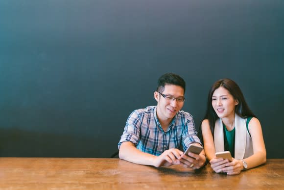 A young couple checks their smartphones.