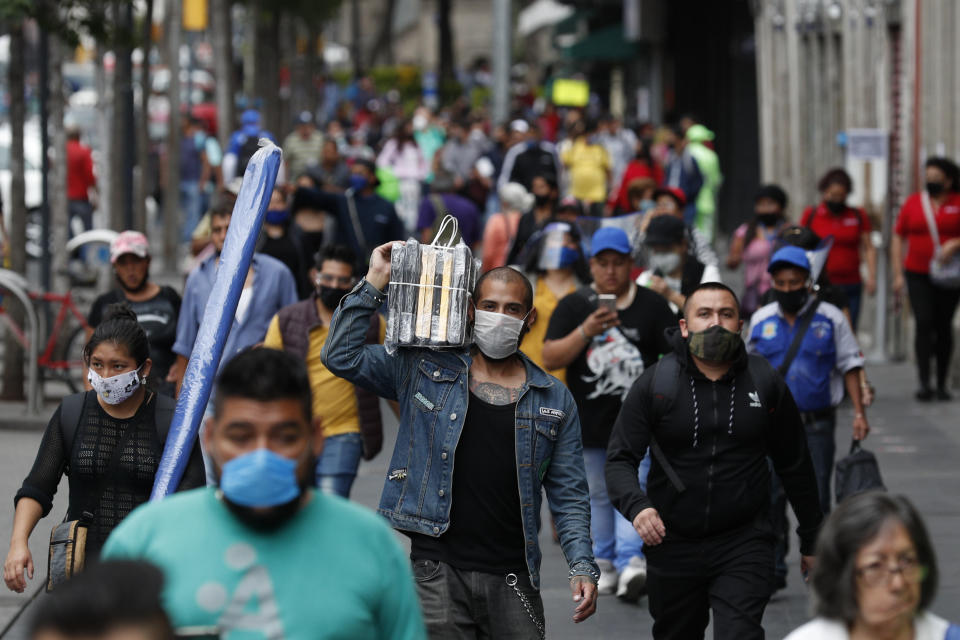 Shoppers and commuters walk along a sidewalk in central Mexico City, Monday, July 6, 2020. After three months of shutdown, officials allowed a partial reopening of the downtown commercial area last week, although COVID-19 cases continue to climb.(AP Photo/Rebecca Blackwell)