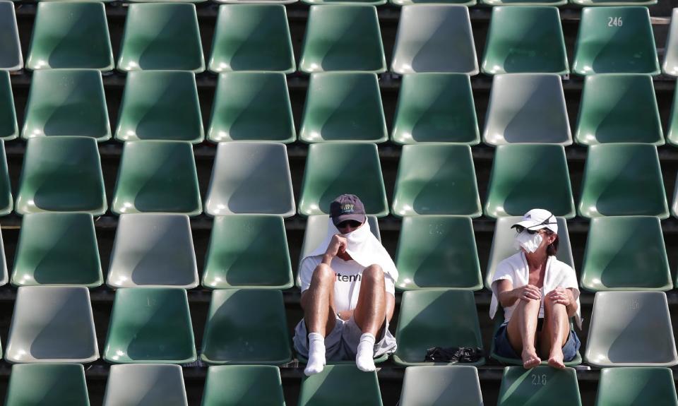 Tennis fans protect themselves from the sun during a first round match at the Australian Open tennis championship in Melbourne, Australia, Tuesday, Jan. 14, 2014.(AP Photo/Aaron Favila)