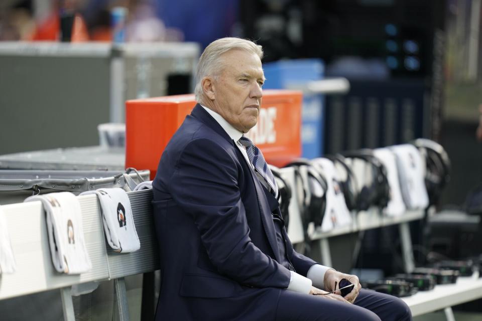 Denver Broncos executive John Elway sits on the bench.