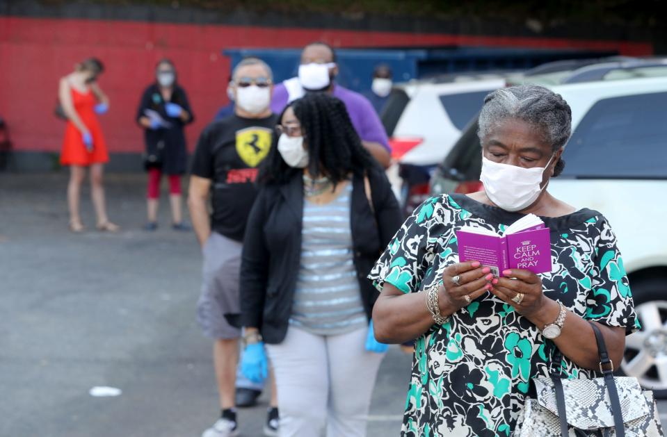 Alcozy Payno-Gamble reads as she waits in line to vote in primary elections at the Nepperhan Community Center in Yonkers, N.Y. June 23, 2020. 