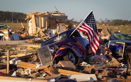 A U.S. flag sticks out the window of a damaged hot rod car in a suburban area after a tornado near Vilonia, Arkansas April 28, 2014. REUTERS/Carlo Allegri