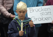 <p>A boy holds candles as he stands in front of a poster reading ‘bridges instead of cleavages’ during a demonstration for democracy and against extremism in Chemnitz, eastern Germany, Sunday, Sept. 2, 2018. (Photo: Jens Meyer/AP) </p>