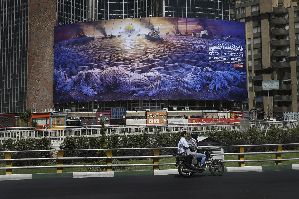 In this Wednesday, May 29, 2019 photo, People drive at Vali-e-Asr Square in downtown Tehran where an anti-Israeli billboard is place ahead of the Al-Quds, Jerusalem, Day, Iran. Mysterious attacks on oil tankers near the strategic Strait of Hormuz show how susceptible one of the world's crucial chokepoints for global energy supplies remains, 30 years after the U.S. Navy and Iran found themselves entangled a similarly shadowy conflict. The so-called "Tanker War" saw American naval ships escort reflagged Kuwaiti oil tankers through the Persian Gulf and the strait after Iranian mines damaged vessels in the region. It culminated in a one-day naval battle between Washington and Tehran, as well as saw America accidentally shoot down an Iranian passenger jet, killing 290 people. (AP Photo/Ebrahim Noroozi)