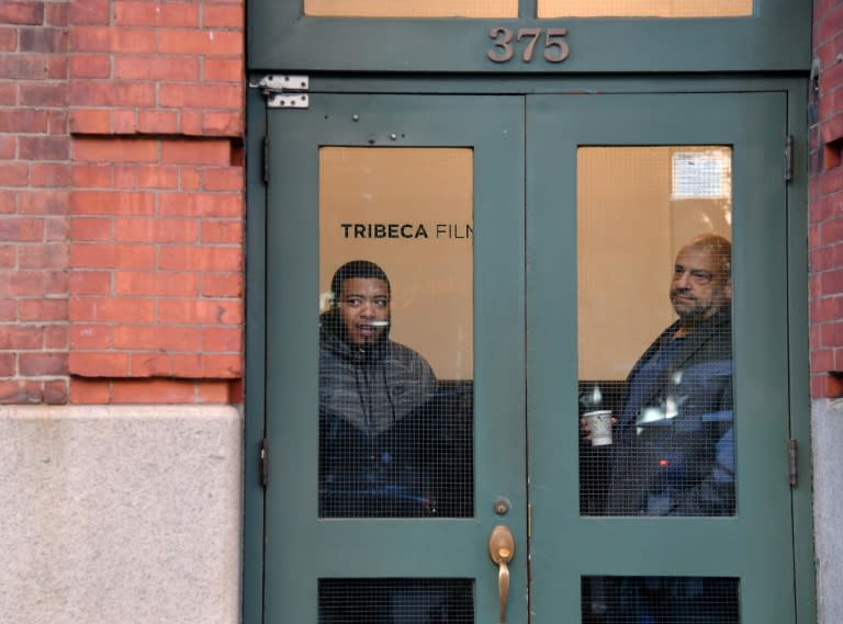 Two men look out the window of Robert de Niro's Tribeca Film Center, in New York City, which was among the latest targets of a wave of bomb alerts