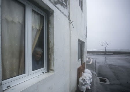 A resident looks out of a window during the passage of hurricane Alex in Ponta Delgada, Azores, Portugal, January 15, 2016. REUTERS/Rui Soares